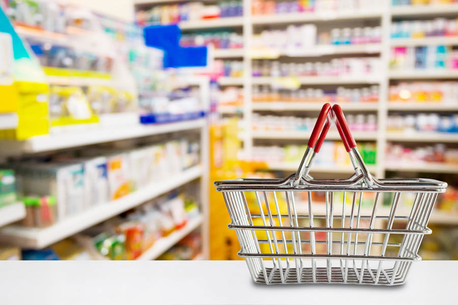 Shopping basket with shelves of medications and over the counter items in the background